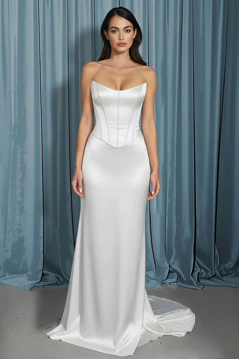 Woman wearing a strapless white gown against a blue curtain background